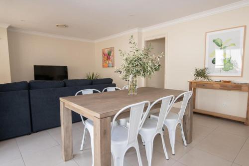a dining room table with white chairs and a blue couch at Park Villa - Near CBD, Spacious, Ideal for Work in Orange