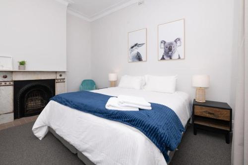 Un dormitorio blanco con una cama azul y blanca y una chimenea en Dunkley House Bathurst Large CBD Heritage Home, Sleeps 10, en Bathurst