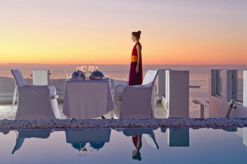 a woman standing on top of a table in the water at Above Blue Suites in Imerovigli