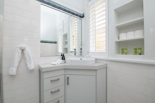 a white bathroom with a sink and a mirror at The Oaks on March Stunning & Elegant CBD Home in Orange