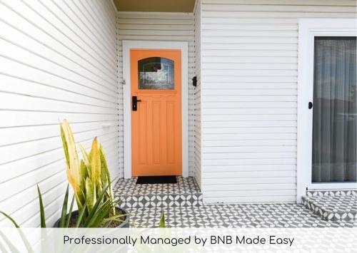an orange door on a white house at Nile Cottage Cosy & Convenient, Close to CBD in Orange
