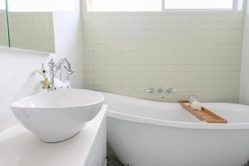 a white bathroom with a tub and a sink at Nile Cottage Cosy & Convenient, Close to CBD in Orange