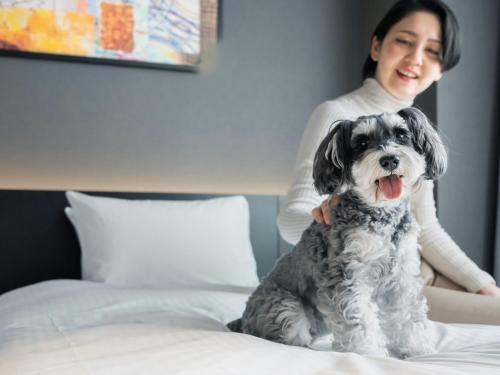a woman sitting on a bed with a dog at hotel anddoggy Kyoto Nijo in Kyoto