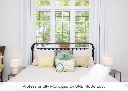a bedroom with a bed with pillows and windows at Summer House in Orange