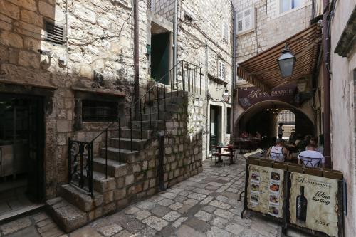 an alley with people sitting at a table in a building at Apartment Ikana in Dubrovnik