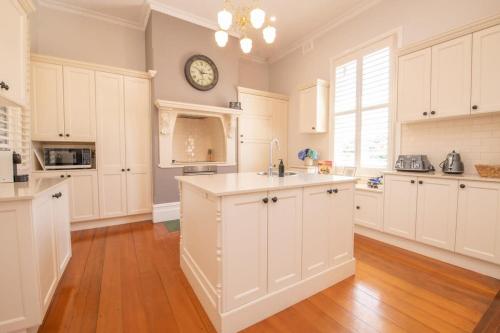 a kitchen with white cabinets and a clock on the wall at LANSDOWNE House in Orange