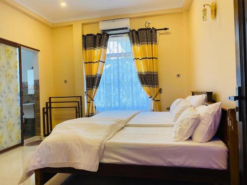 a bedroom with a bed with yellow walls and a window at WIMAL PALACE in Jaffna