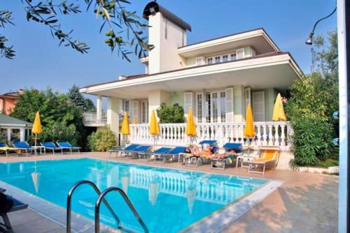 a house with a swimming pool with chairs and umbrellas at Hotel GARDENIA & Villa CHARME Adults Friendly 10Plus in Bardolino