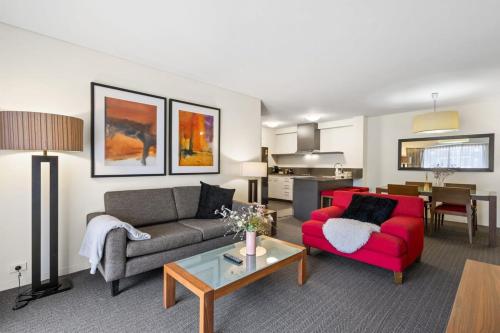 a living room with a red couch and a table at Cosy Apartment in the Heart of Perth CBD in Perth