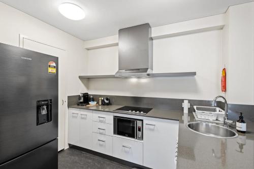 a kitchen with a stainless steel refrigerator and a sink at Cosy Apartment in the Heart of Perth CBD in Perth