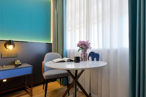 a table and a chair with a vase of flowers on it at R Royalss Hotel, Yulin Yuxing Square in Yulin