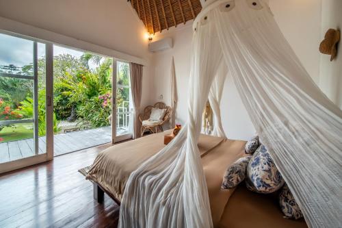 a bedroom with a bed with a mosquito net at Villa Moana Poe Uluwatu in Uluwatu
