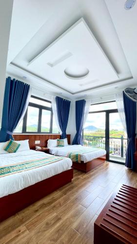 two beds in a room with blue drapes at Golden Apple Villa Đà Lạt in Khu Chi Lăng