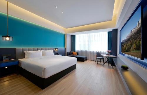 a bedroom with a large white bed and a desk and a room at R Royalss Hotel, Yulin Yuxing Square in Yulin