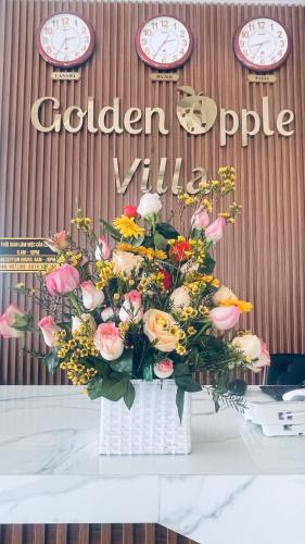 a vase filled with flowers on a table with clocks at Golden Apple Villa Đà Lạt in Khu Chi Lăng