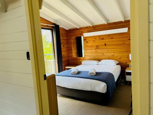 a bedroom with a bed in a wooden cabin at Bicheno by the Bay in Bicheno