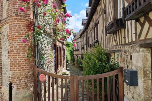 Une allée avec des fleurs sur le côté des bâtiments dans l'établissement La Parenthèse Saint Jean - studio city center, à Honfleur