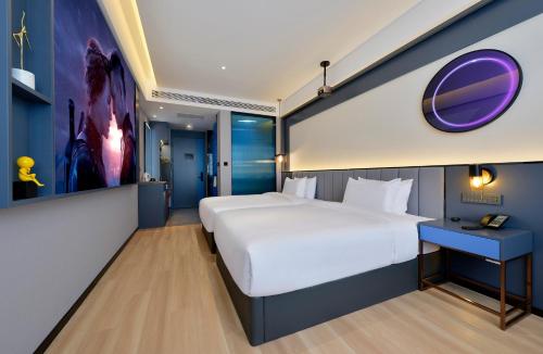 a bedroom with a large bed and a blue wall at R Royalss Hotel, Yulin Yuxing Square in Yulin