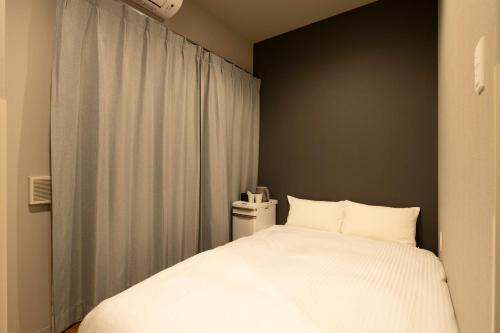 a bedroom with a white bed and a window at Grids Tokyo Ueno Hotel&Hostel in Tokyo