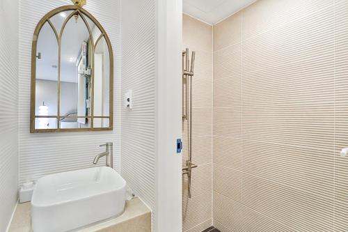 a white bathroom with a sink and a mirror at Gyeongju Hotel Gonggan in Gyeongju