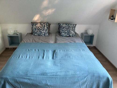 a large blue bed in a room with two tables at Bazsalikom-Apartman in Mezőkövesd