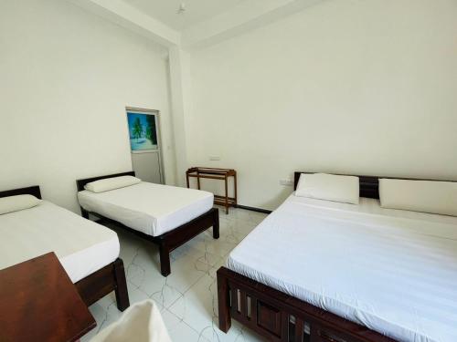 Habitación con 2 camas y una silla. en ZIMBAY Guest House, en Arugam Bay