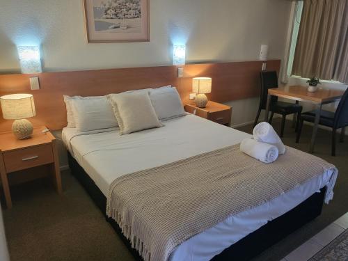 Bundaberg International Motor Inn في بوندابرج: غرفة فندق عليها سرير وفوط