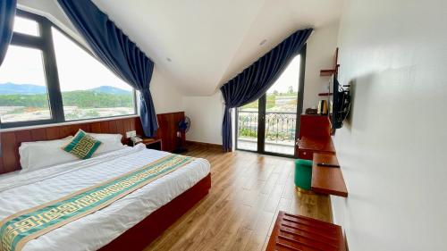a bedroom with a large bed and large windows at Golden Apple Villa Đà Lạt in Khu Chi Lăng