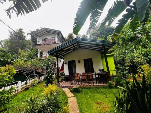 a small yellow and white house with a porch at Rest Full Homestay in Ella