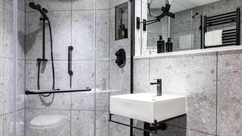 La salle de bains est pourvue d'un lavabo blanc et d'une douche. dans l'établissement voco Leicester, an IHG Hotel, à Leicester