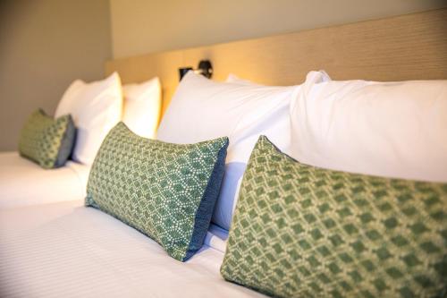 1 cama con almohadas blancas y almohadas verdes en Nightcap at Marine Hotel Cardwell, en Cardwell