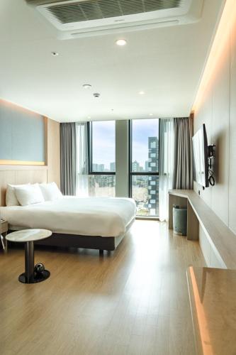 a hotel room with a bed and a large window at Jeju Bolton Hotel in Jeju