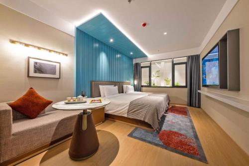a bedroom with a bed and a couch and a window at CityNote希诺酒店(广州北京路步行街新大新店) in Guangzhou