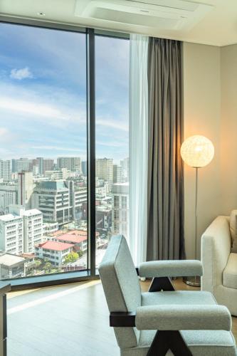 a living room with a chair and a large window at Jeju Bolton Hotel in Jeju