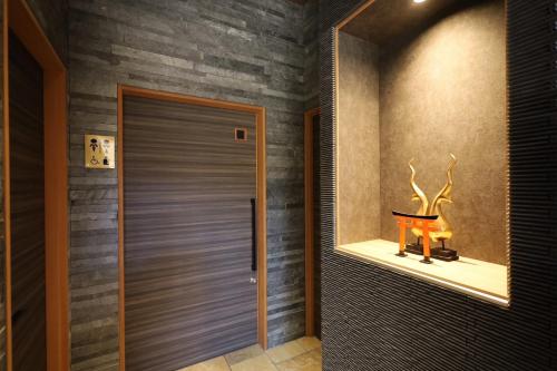 a hallway with a door and a shelf with a statue at HOTEL CUORE Kyoto Shijo Omiya in Kyoto