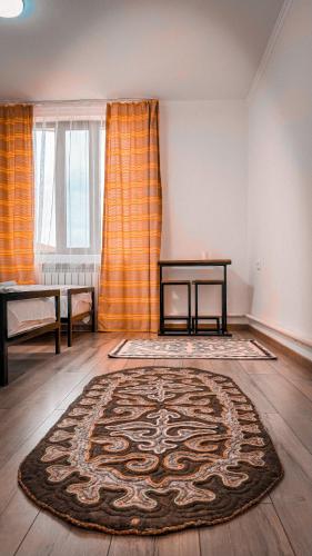 a room with a rug on the floor with a table at Kezgin Guest House in Naryn