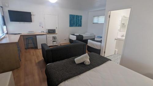 Habitación pequeña con cama, escritorio y cocina. en Moffat Beach Motel Caloundra en Caloundra