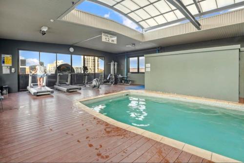 a gym with a swimming pool and a man on a treadmill at Large Luxe Penthouse fully equipped Perth CBD in Perth