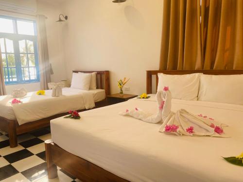 um quarto de hotel com duas camas com flores em Vida Loca Sunset Beach Resort em Phu Quoc