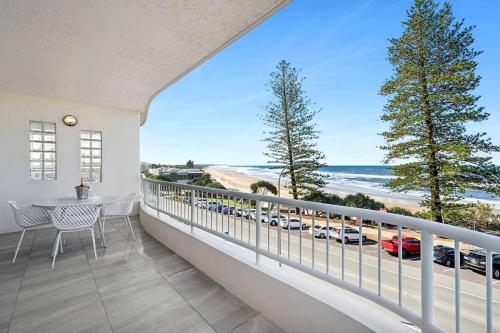 Un balcón con mesa y sillas y vista a la playa. en Luxurious Beachfront Penthouse, en Coolum Beach
