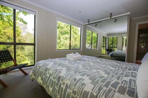 a bedroom with a large bed and large windows at Alderwood in Bright