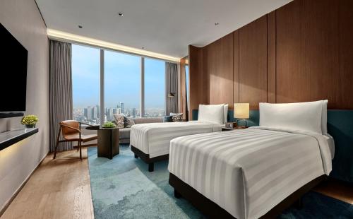 two beds in a hotel room with a view at Pan Pacific Jakarta in Jakarta