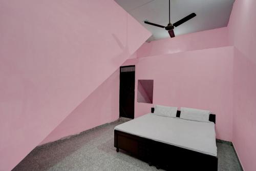 OYO Hotel star palace في نويدا: غرفة نوم وردية مع سرير ومروحة سقف