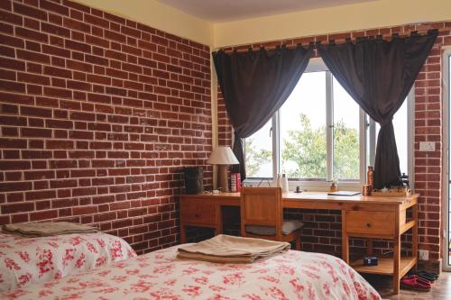 a bedroom with two beds and a desk and a brick wall at Les Terrasses Himalayan Resort in Charikot