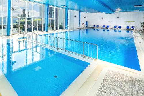 a large indoor swimming pool with blue water at AHORN Hotel Am Fichtelberg in Kurort Oberwiesenthal