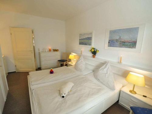 a bedroom with a white bed with a stuffed animal on it at Holiday apartment on the golf course F35E in Fehmarn