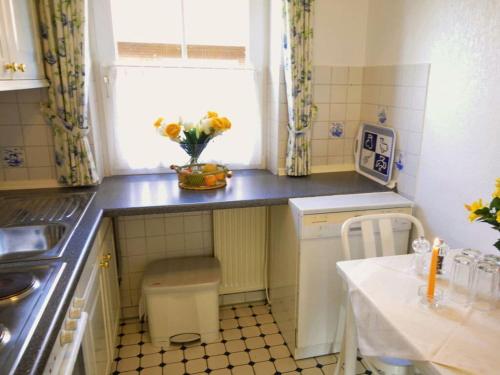 a small kitchen with a vase of flowers on the counter at Holiday apartment on the golf course F35E in Fehmarn