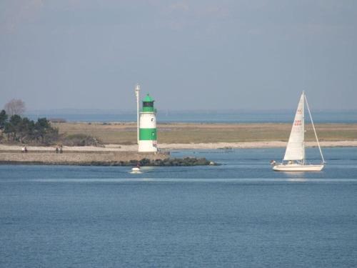 a sailboat in the water with a lighthouse in the background at Tern in the Molenhuus in Kappeln