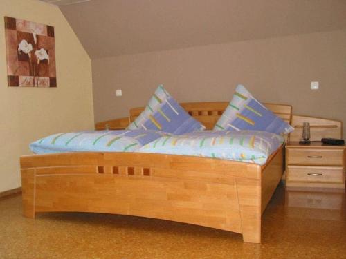 una cama de madera con almohadas azules en una habitación en Sabine Comfortable holiday residence, en Wollmerschied