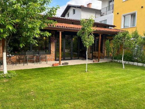 a house with a green lawn in front of it at Horizont Dobrinishte in Dobrinishte